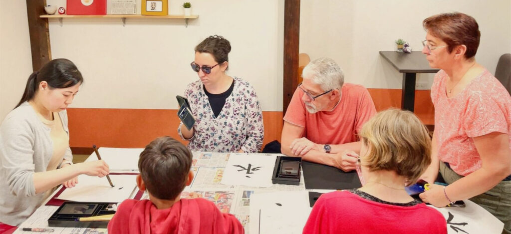Wide shot of guests practicing Japanese calligraphy during a cultural experience at Pongyi.